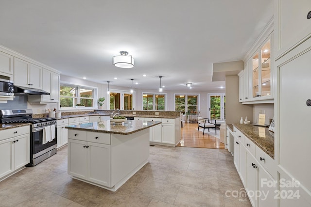 kitchen with white cabinets, hanging light fixtures, gas stove, and a kitchen island