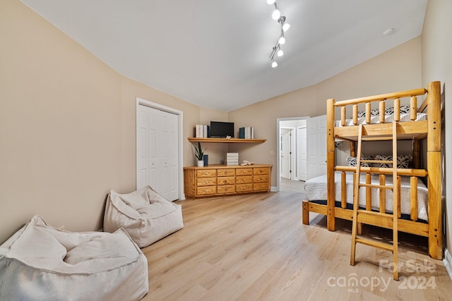 bedroom featuring light wood-type flooring, a closet, and lofted ceiling