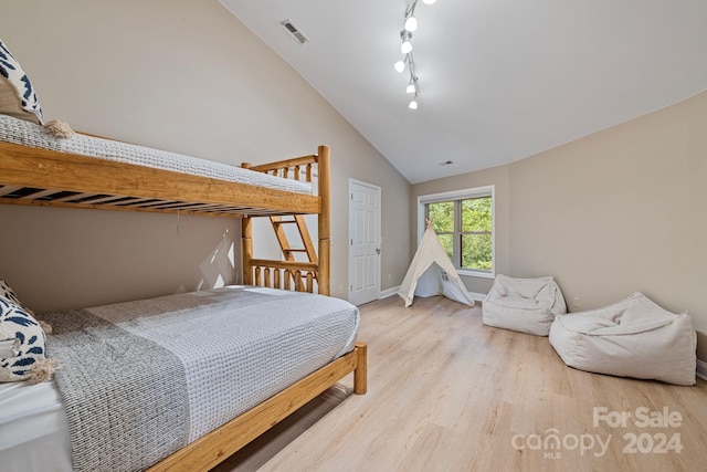 bedroom with light hardwood / wood-style floors and high vaulted ceiling