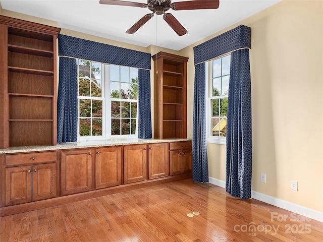 empty room with a wealth of natural light, ceiling fan, and light wood-type flooring