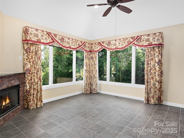 interior space featuring ceiling fan, lofted ceiling, a fireplace, and tile patterned flooring