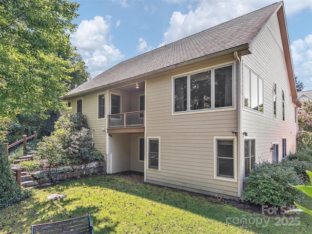 rear view of house with a yard and a balcony