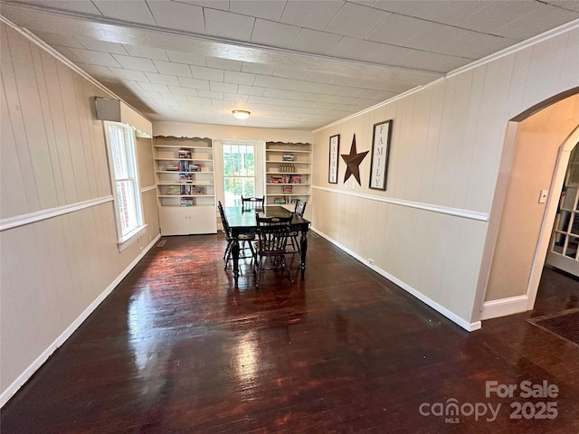 unfurnished dining area featuring ornamental molding, dark hardwood / wood-style floors, and built in features