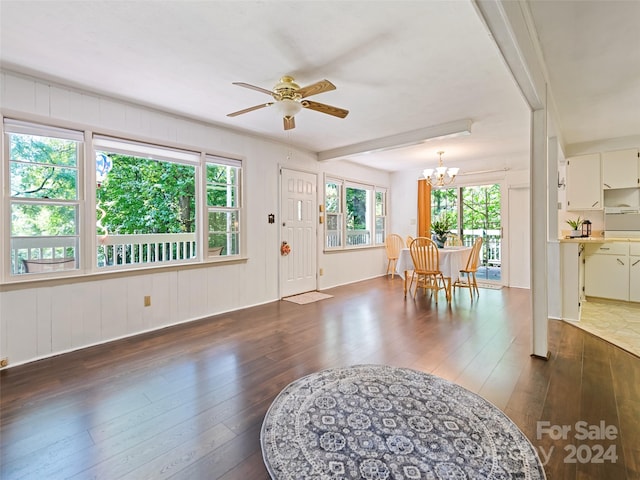 interior space featuring ceiling fan with notable chandelier, a healthy amount of sunlight, and dark hardwood / wood-style flooring