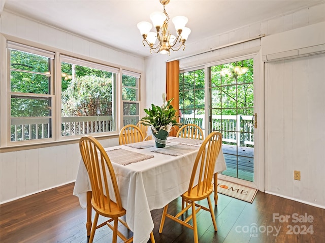 dining room with an inviting chandelier, wood walls, dark hardwood / wood-style floors, and plenty of natural light