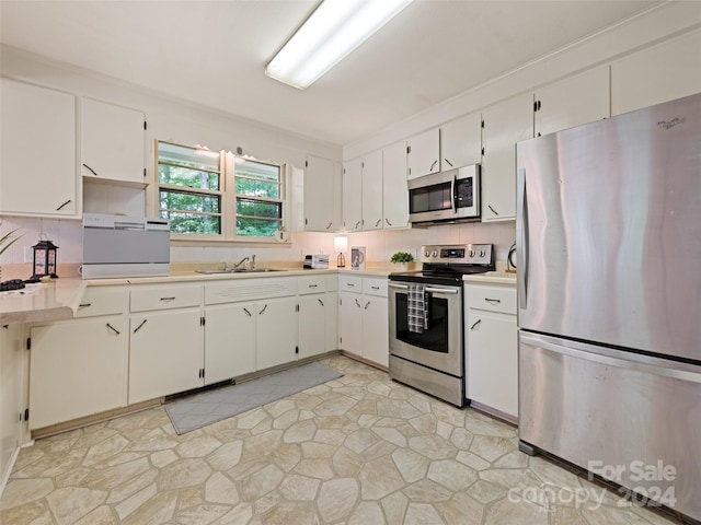 kitchen featuring stainless steel appliances, sink, decorative backsplash, and white cabinetry