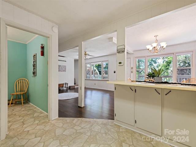 kitchen featuring hanging light fixtures, ceiling fan with notable chandelier, light hardwood / wood-style floors, and ornamental molding