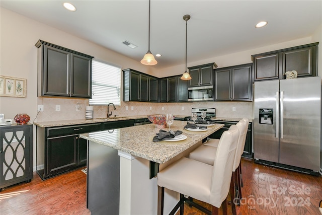 kitchen featuring pendant lighting, dark hardwood / wood-style floors, sink, a kitchen island, and appliances with stainless steel finishes