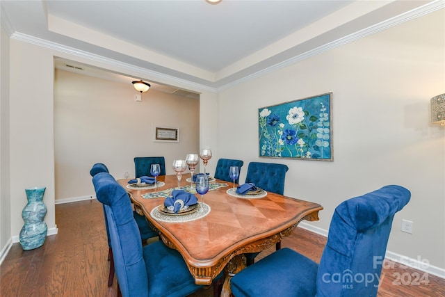 dining area with ornamental molding, a tray ceiling, and dark hardwood / wood-style flooring