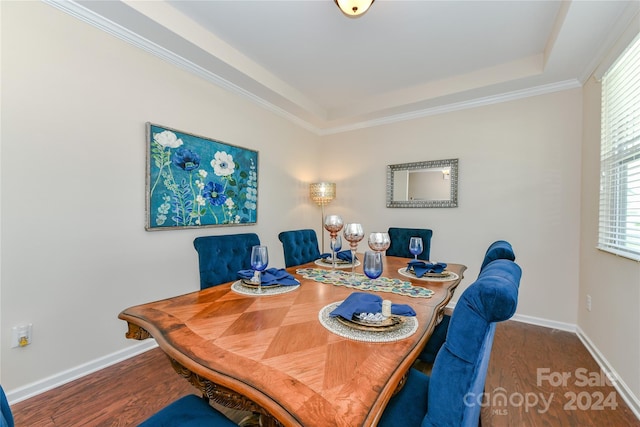 dining space with ornamental molding, a tray ceiling, and dark hardwood / wood-style floors