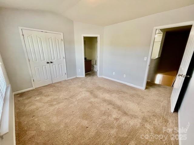 4327 Kobuk Ln, Charlotte, NC 28269 - unfurnished bedroom featuring baseboards, light carpet, lofted ceiling, and a closet