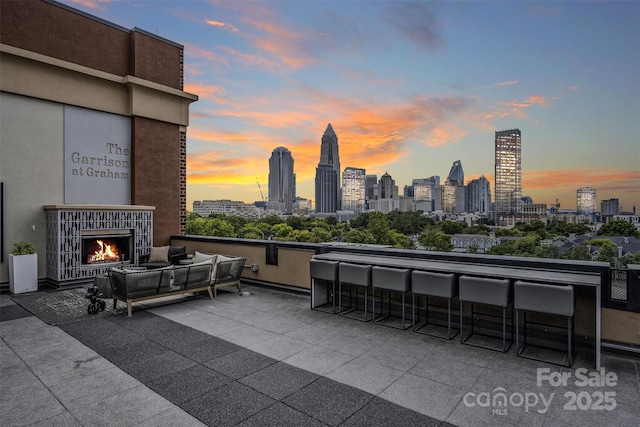 patio terrace at dusk with a bar and an outdoor living space with a fireplace