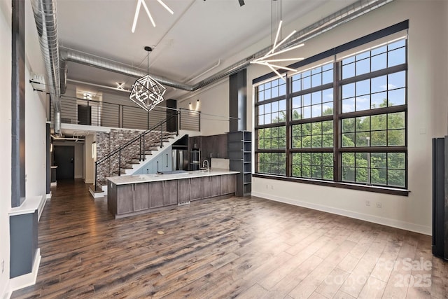 kitchen with a towering ceiling, sink, kitchen peninsula, and dark wood-type flooring