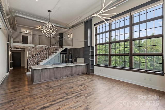 kitchen with dark hardwood / wood-style flooring, dark brown cabinets, an inviting chandelier, and kitchen peninsula