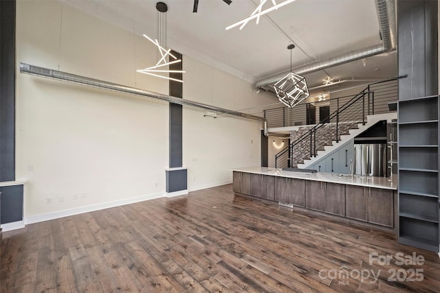 kitchen featuring a towering ceiling, dark hardwood / wood-style flooring, pendant lighting, and dark brown cabinets