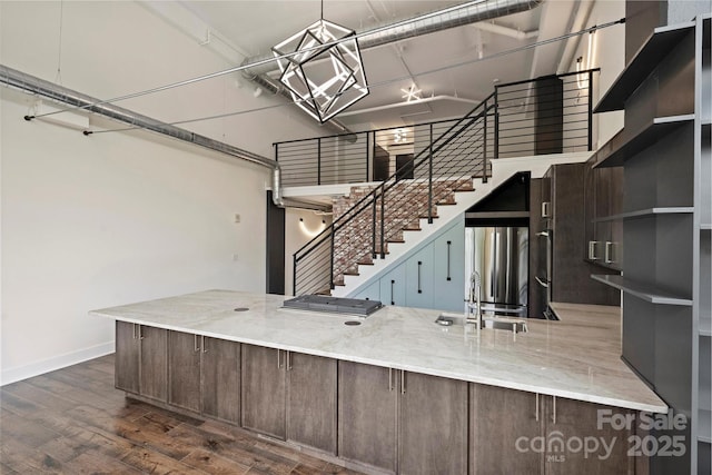 kitchen with a towering ceiling, stainless steel fridge, dark hardwood / wood-style floors, sink, and decorative light fixtures