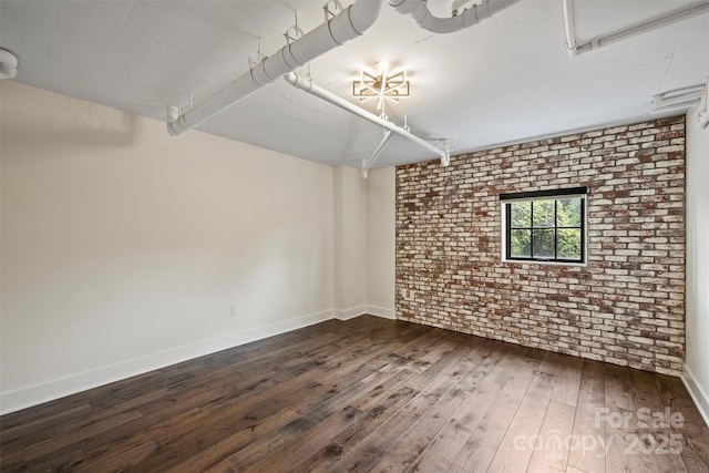 spare room with dark hardwood / wood-style flooring and brick wall