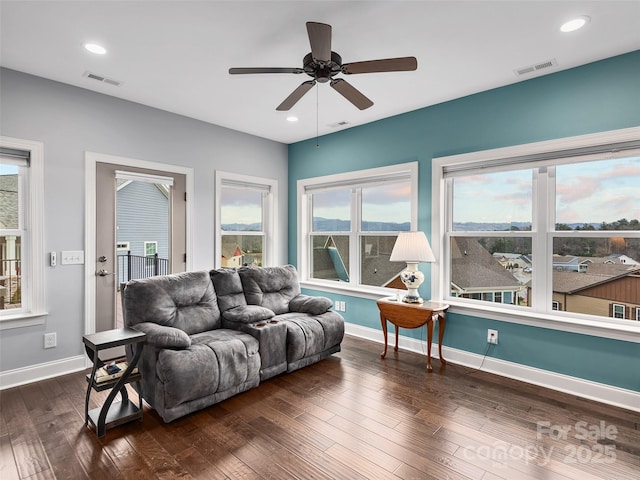 living room featuring dark wood-type flooring and ceiling fan