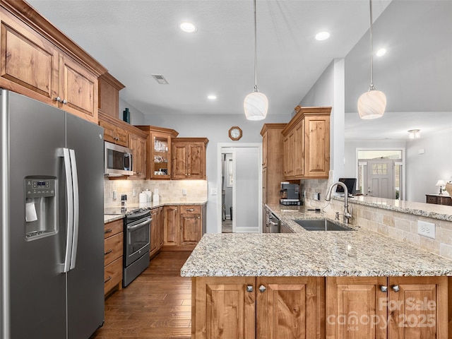 kitchen featuring pendant lighting, stainless steel appliances, kitchen peninsula, and sink