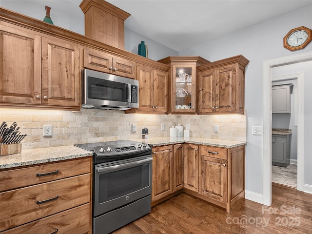 kitchen featuring light stone counters, backsplash, dark wood-type flooring, and stainless steel appliances