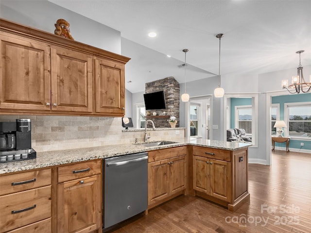 kitchen featuring sink, dishwasher, light stone counters, decorative light fixtures, and kitchen peninsula