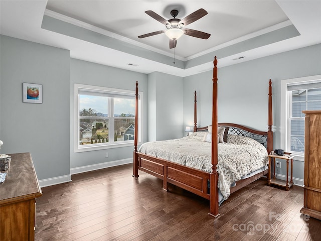 bedroom with a raised ceiling, ornamental molding, dark hardwood / wood-style floors, and ceiling fan