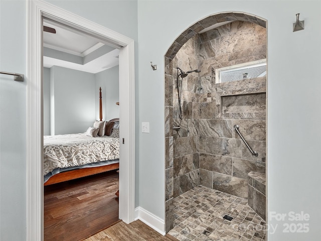 bathroom with ornamental molding, wood-type flooring, and a tile shower