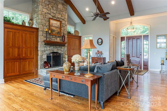 living room with a fireplace, beam ceiling, ceiling fan, and light hardwood / wood-style flooring