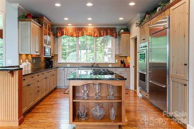 kitchen with stainless steel appliances, crown molding, and light hardwood / wood-style floors