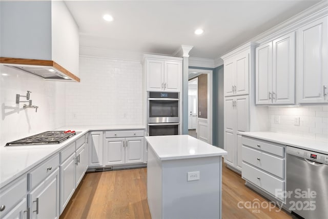 kitchen with white cabinetry, stainless steel appliances, a kitchen island, and custom exhaust hood