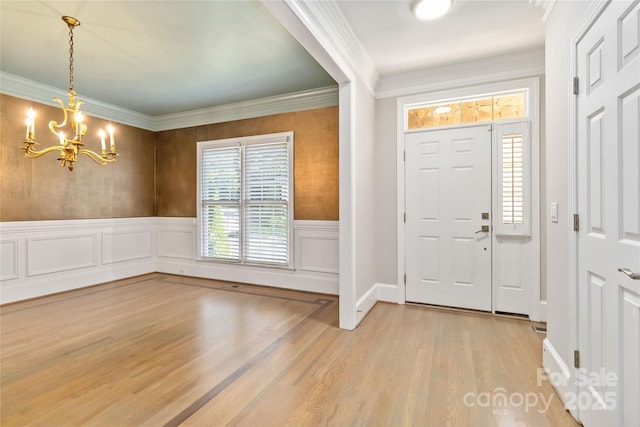 foyer entrance with hardwood / wood-style flooring, ornamental molding, and a chandelier