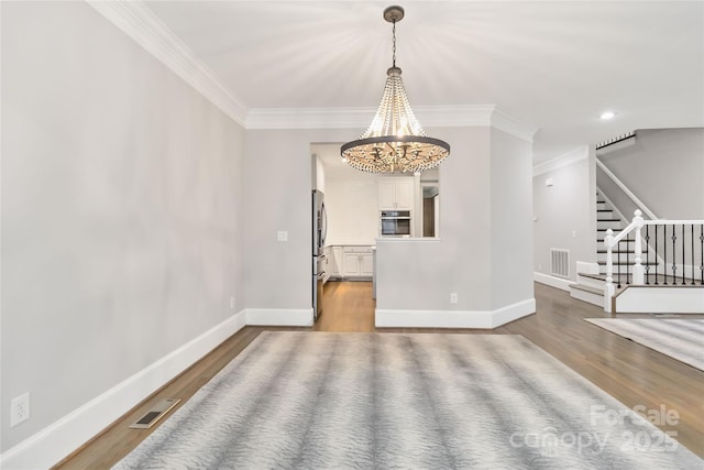 unfurnished room featuring wood-type flooring, a notable chandelier, and crown molding