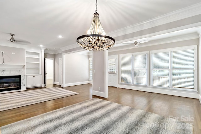 unfurnished living room featuring dark hardwood / wood-style flooring, crown molding, a high end fireplace, and ceiling fan