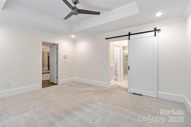 unfurnished bedroom with ornamental molding, a barn door, a raised ceiling, and light carpet