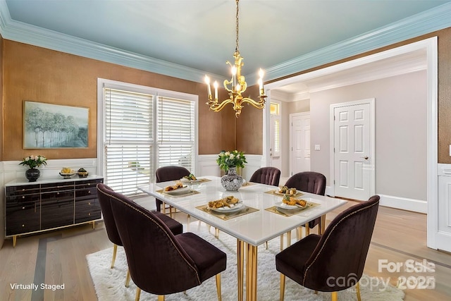 dining space featuring a notable chandelier, crown molding, and light wood-type flooring