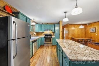 kitchen featuring wood walls, a center island, hanging light fixtures, light hardwood / wood-style floors, and stainless steel appliances