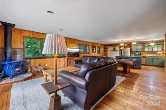 living room with hardwood / wood-style floors, pool table, a wood stove, and wooden walls