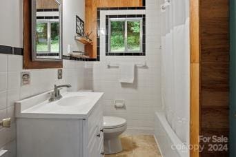 full bathroom with toilet, vanity, tile walls, and shower / tub combo