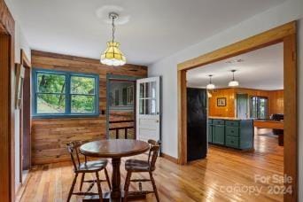 dining space featuring light hardwood / wood-style flooring and wood walls