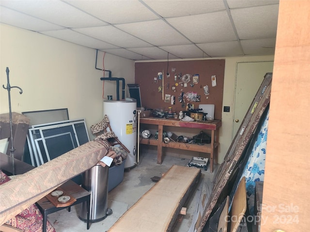 basement featuring a drop ceiling, a workshop area, and gas water heater