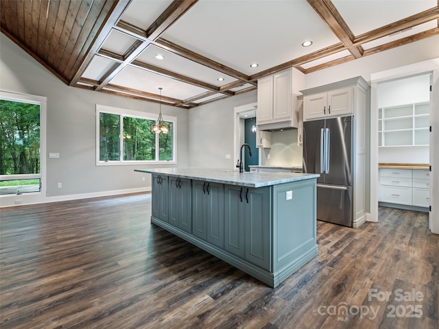 kitchen with stainless steel fridge, dark hardwood / wood-style flooring, light stone counters, a kitchen island with sink, and white cabinets