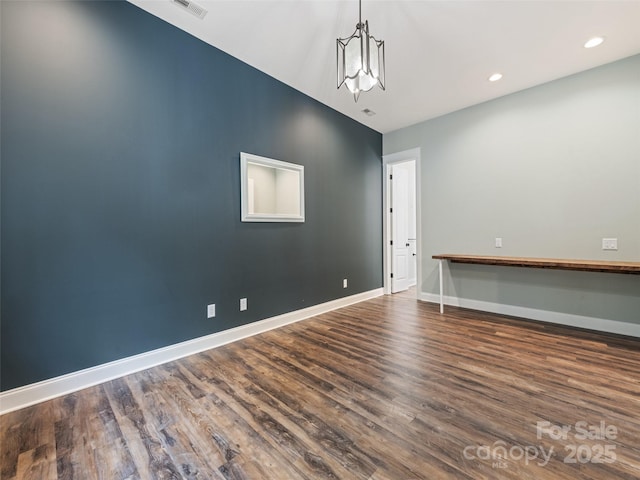 empty room featuring dark hardwood / wood-style floors and an inviting chandelier