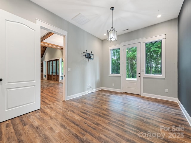 unfurnished room with dark hardwood / wood-style floors and an inviting chandelier