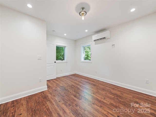 spare room with a wall mounted air conditioner and dark wood-type flooring