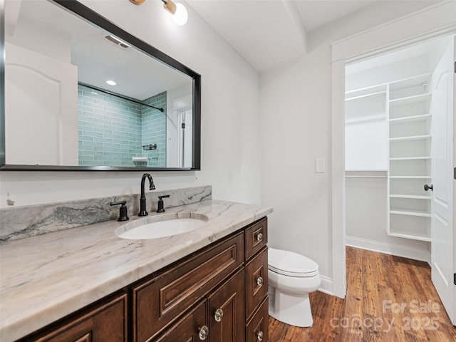 bathroom featuring vanity, toilet, wood-type flooring, and walk in shower