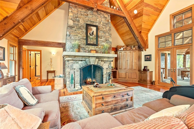 living room featuring a stone fireplace, hardwood / wood-style floors, beamed ceiling, and high vaulted ceiling