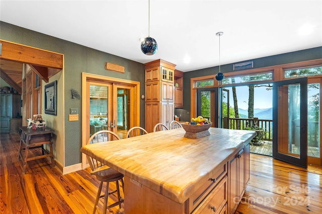 kitchen featuring a kitchen breakfast bar, hanging light fixtures, a kitchen island, and dark hardwood / wood-style flooring