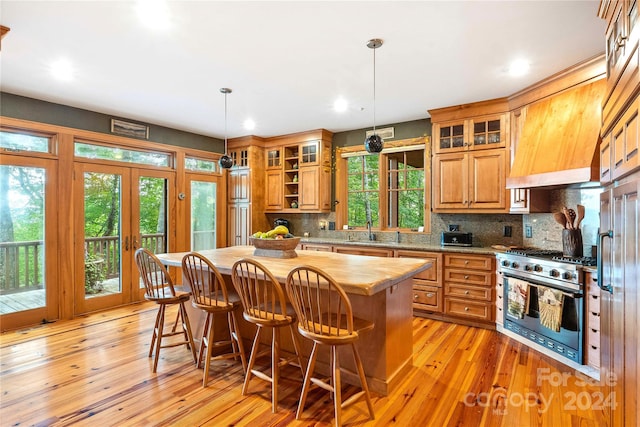 kitchen featuring light hardwood / wood-style floors, a center island, stainless steel stove, and plenty of natural light