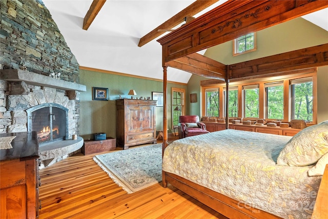 bedroom with wood-type flooring, a stone fireplace, beamed ceiling, and high vaulted ceiling