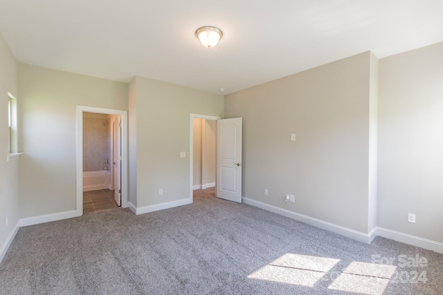 unfurnished bedroom with ensuite bath and light carpet